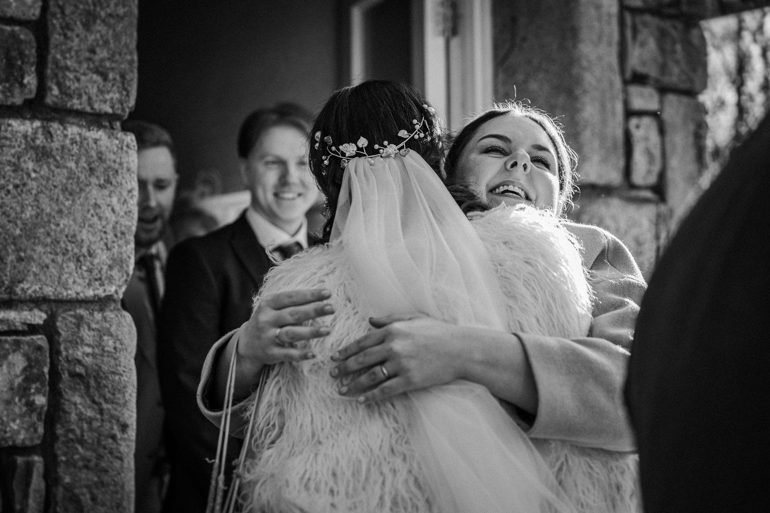 Black and white photo collage showing emotional embraces and candid moments at a wedding celebration.