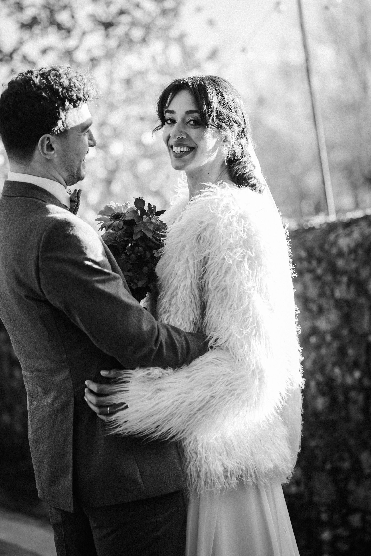 A series of black and white wedding photos showing intimate moments between a couple in a feathered white dress and suit.