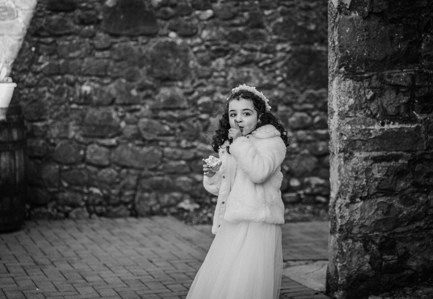 A series of black and white wedding photos showing romantic moments against a rustic stone wall backdrop.