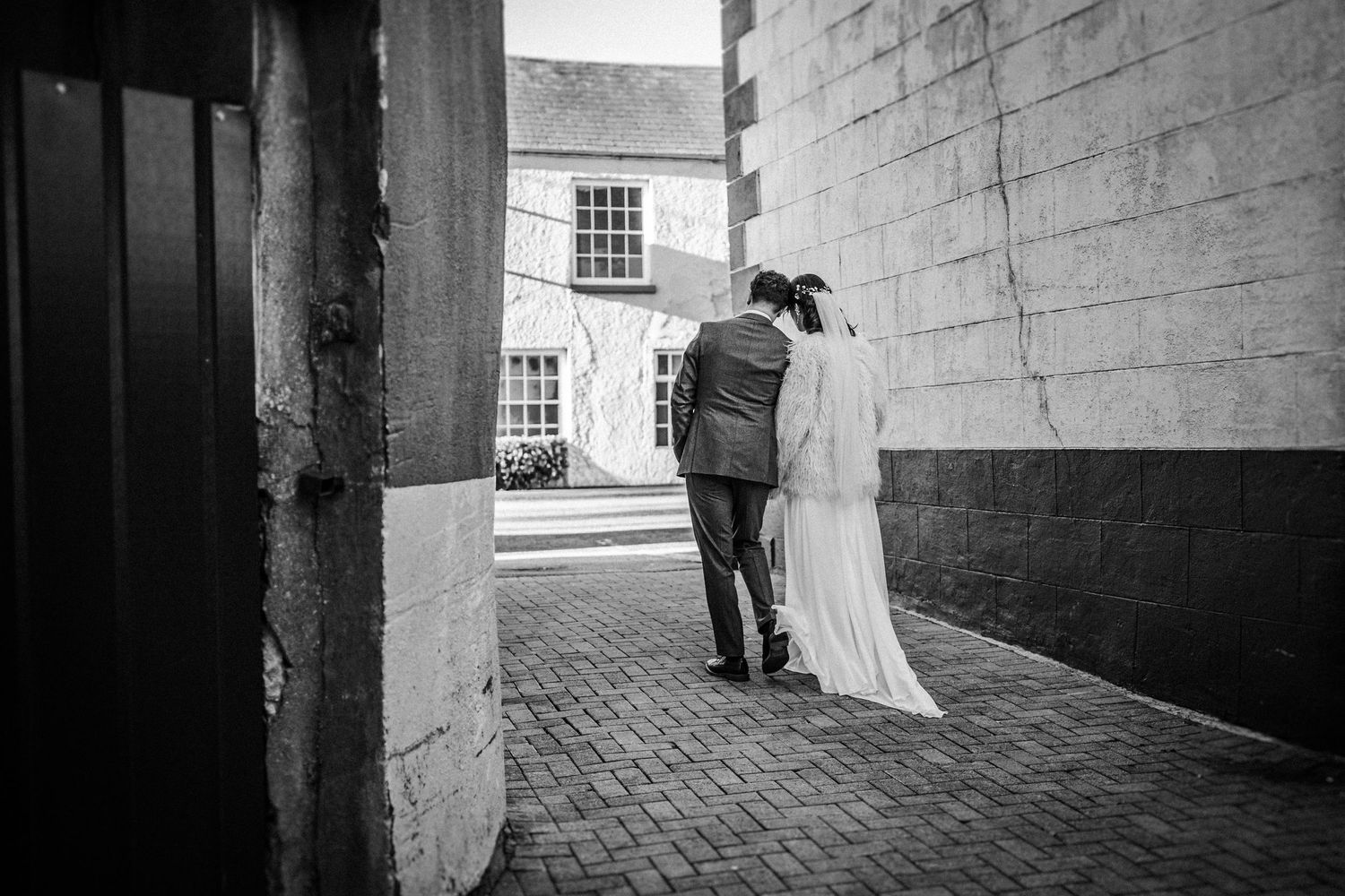 Black and white wedding photos showing couple walking through stone archways and corridors.