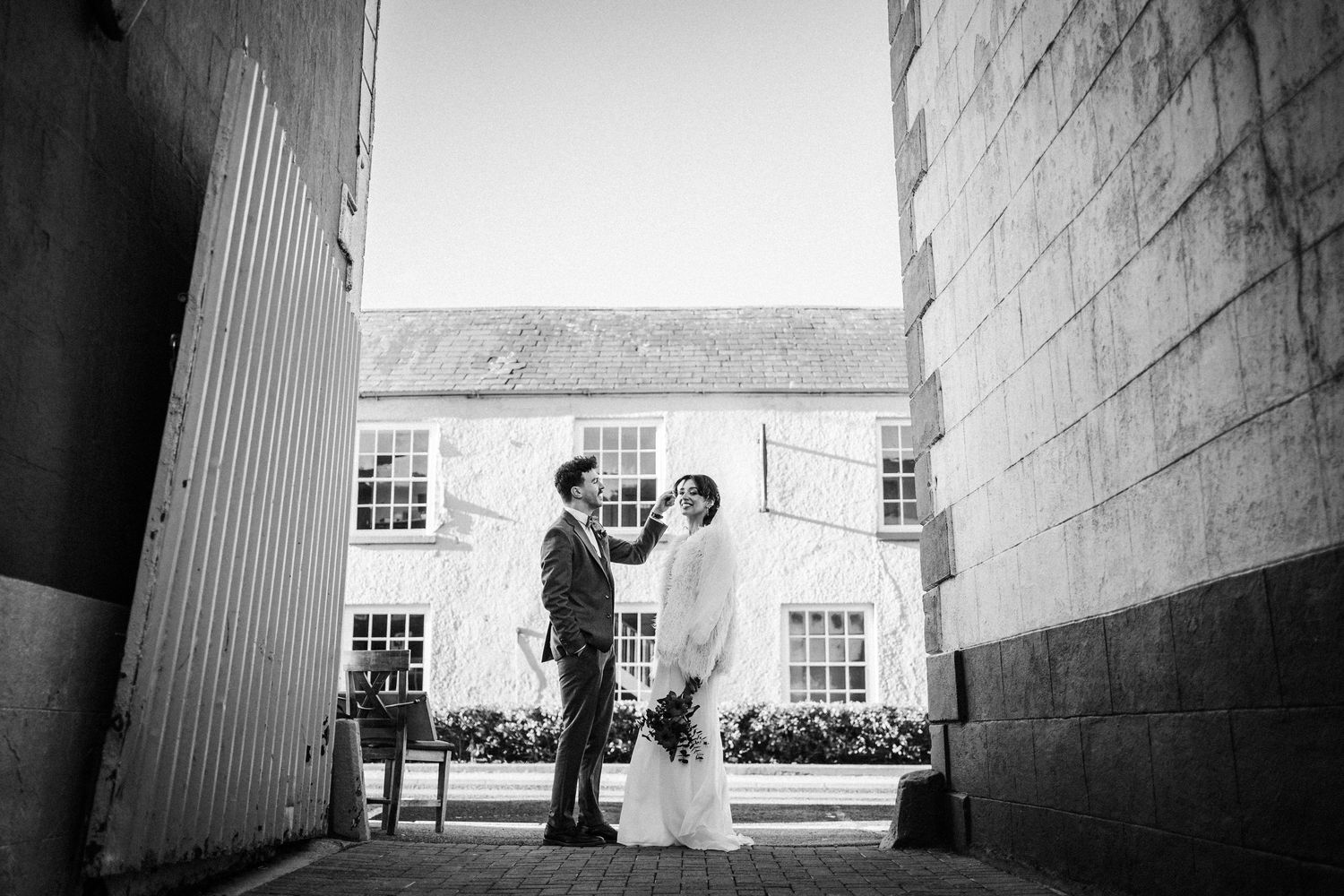 Black and white wedding photo series showing couple and wedding party in dramatic architectural framing.