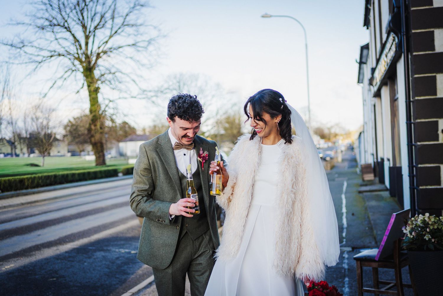 Winter wedding photos with bare trees showing couple in formal attire walking outdoors.