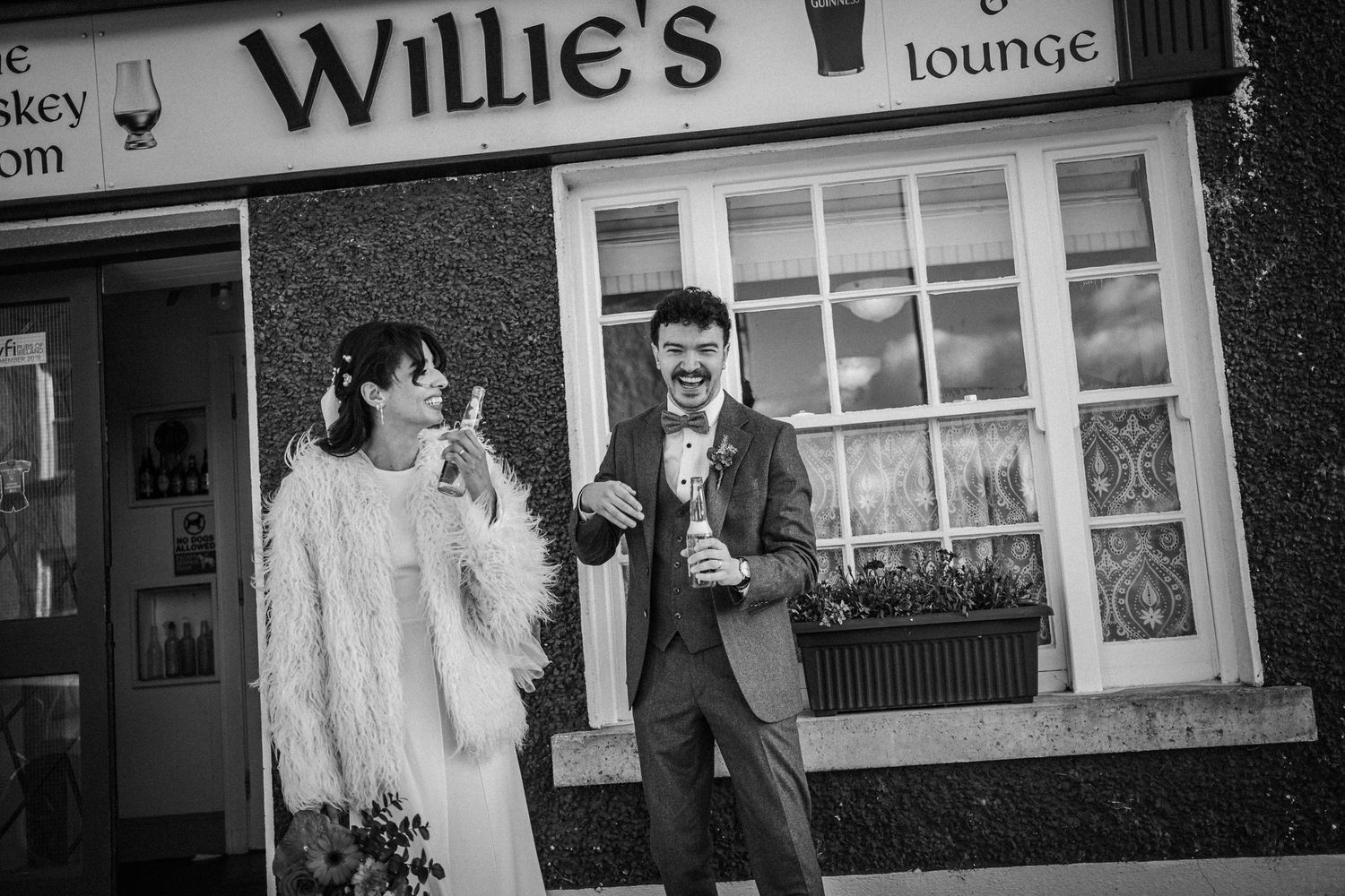 A couple shares a romantic moment outside Willie's Lounge, with the bar's illuminated signage visible in the background.