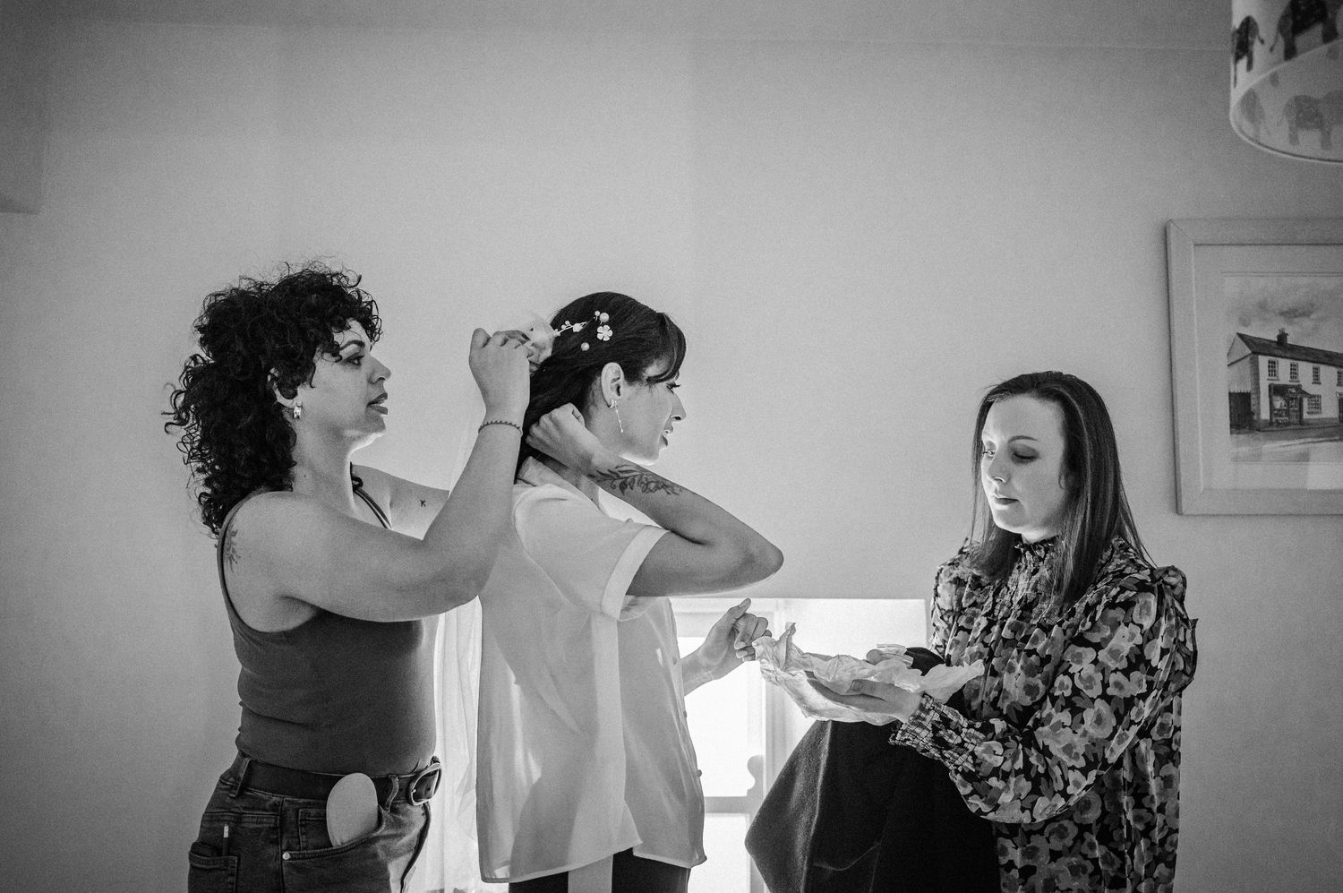 Three people getting ready in a casual indoor setting captured in black and white photography.