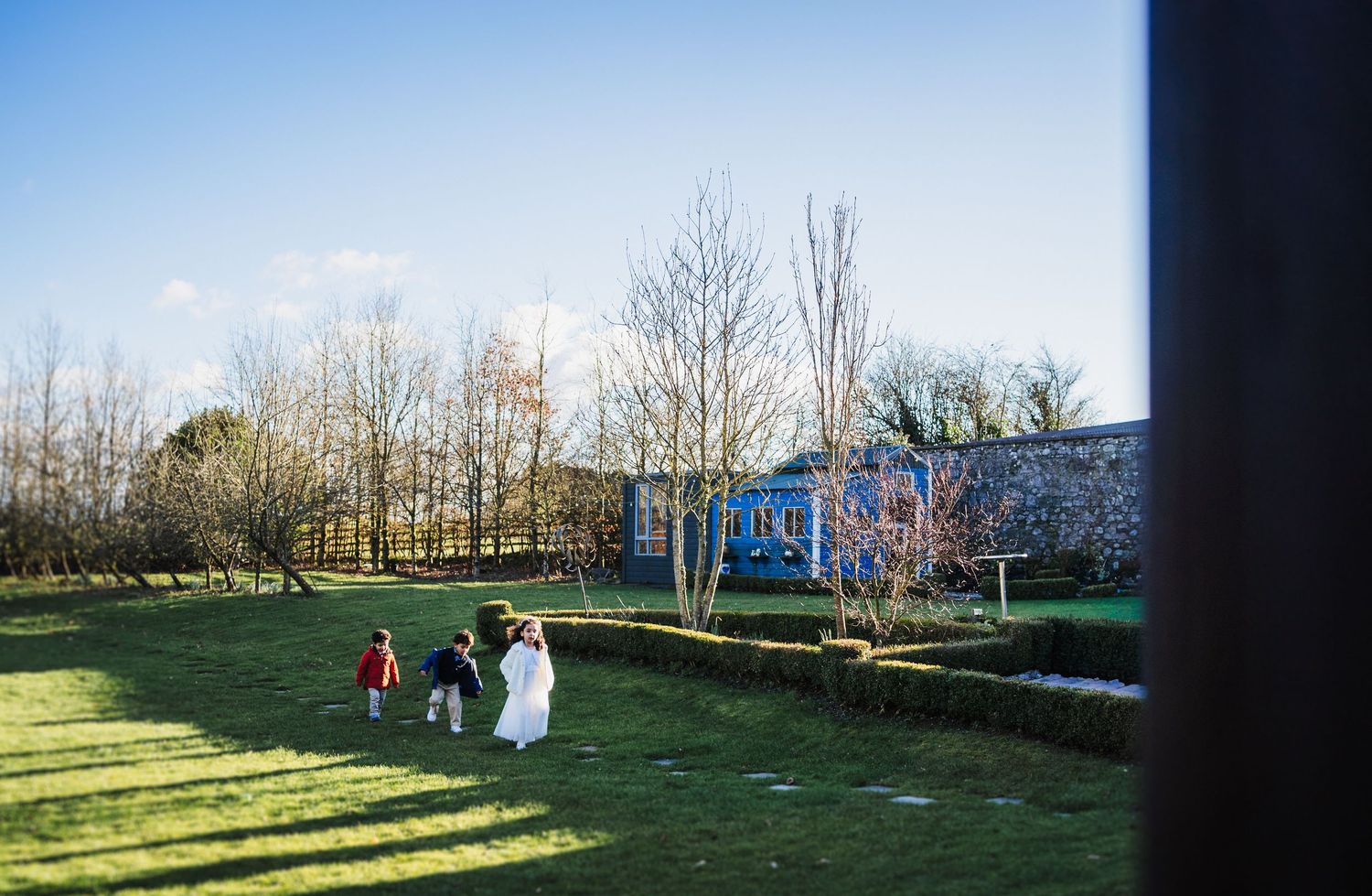 A panoramic view of a green park with bare trees and people enjoying outdoor activities on a sunny day.