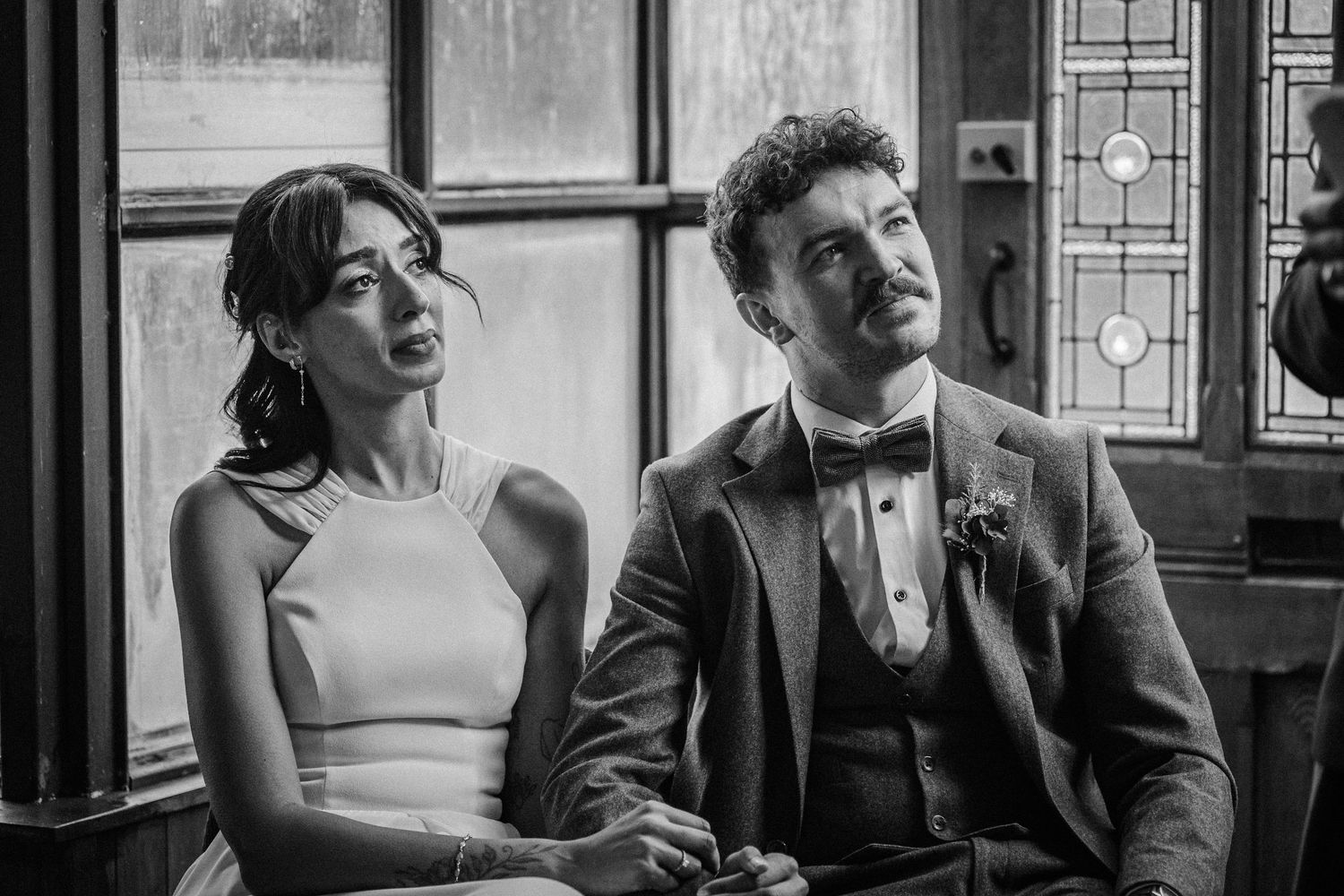 A black and white photo series shows a couple in vintage attire having an intimate conversation at a restaurant table.