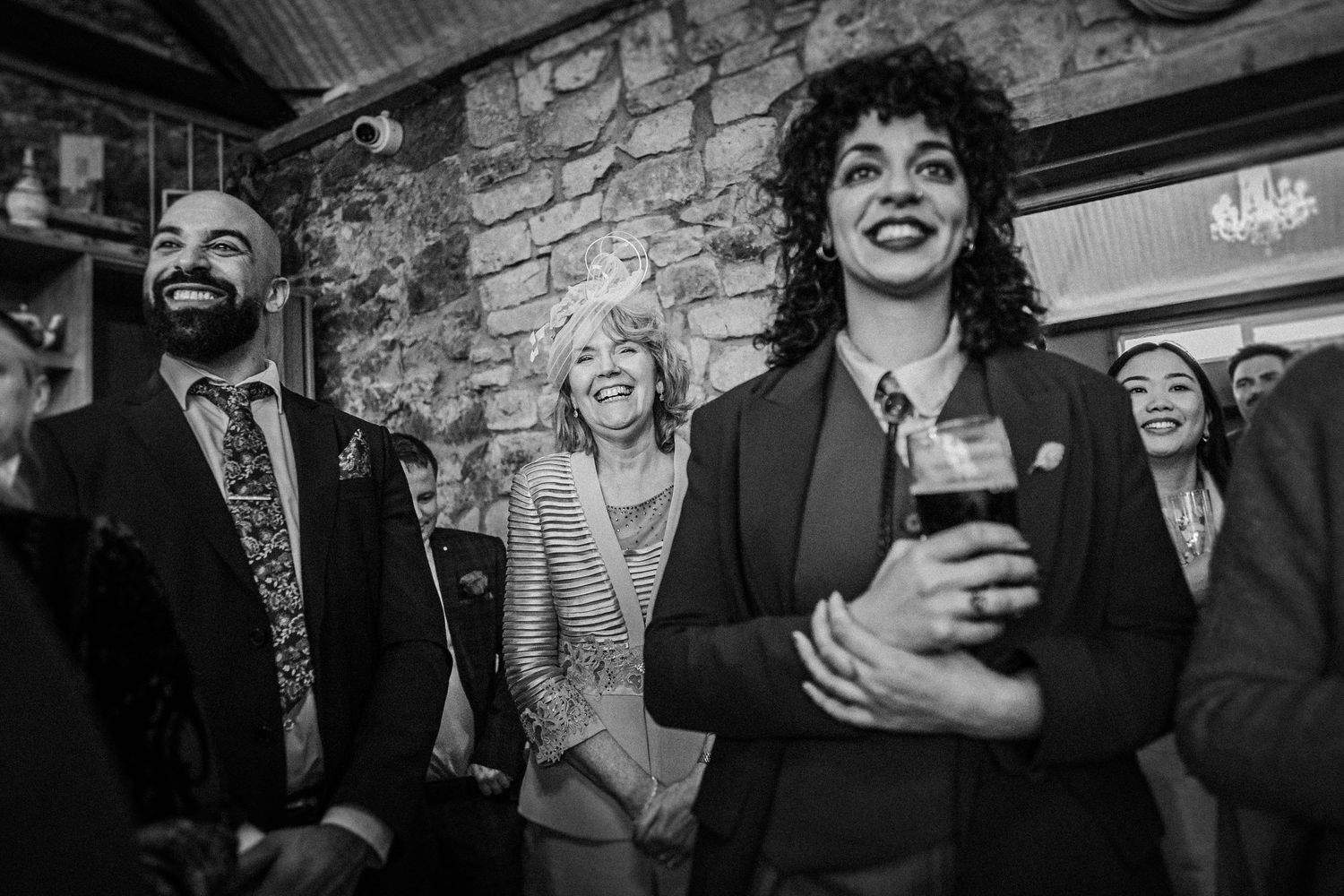 A black and white photo series showing joyful wedding guests laughing and embracing during a celebration.