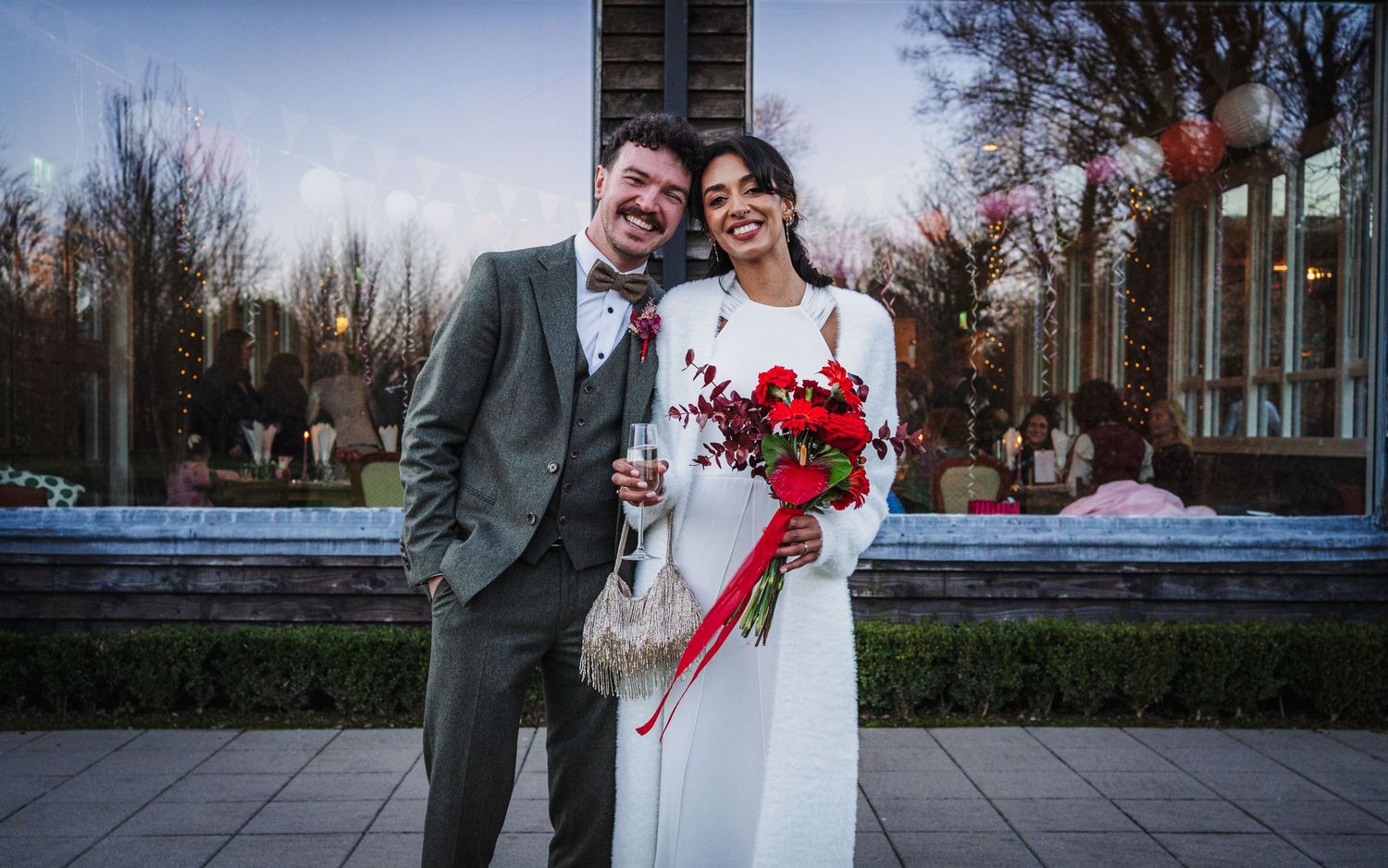 A couple in wedding attire walks together outdoors during their winter wedding celebration.