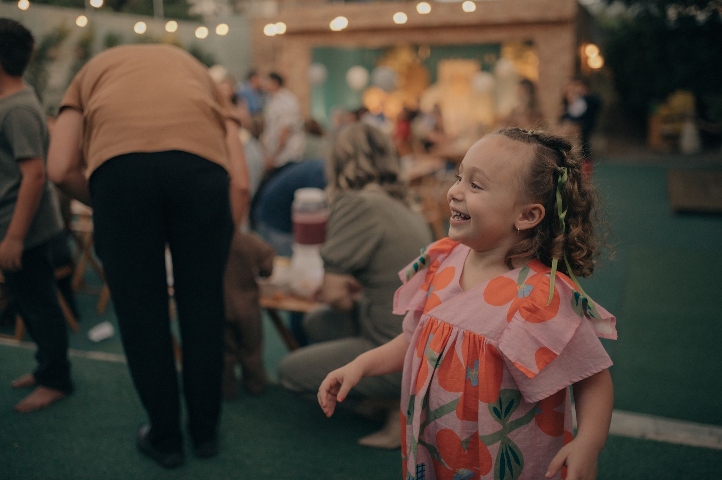 A child in a coral dress enjoys a lively indoor celebration.