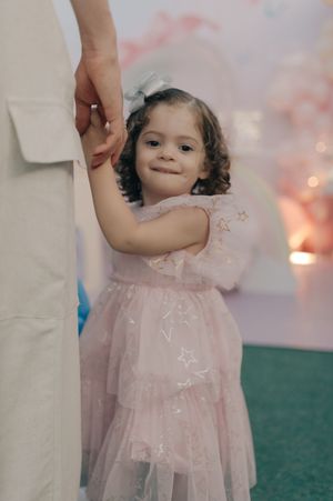 A young child in a pink tulle dress smiles during a celebration with soft lighting.