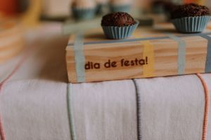 Chocolate cupcakes displayed with a wooden sign reading 'dia de festa' on a white cloth.