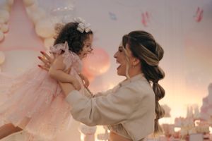 A joyful moment during a celebration with a pink tulle dress and warm lighting in the background.