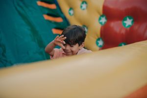 Child peeking over a colorful playground structure with stars in the background.