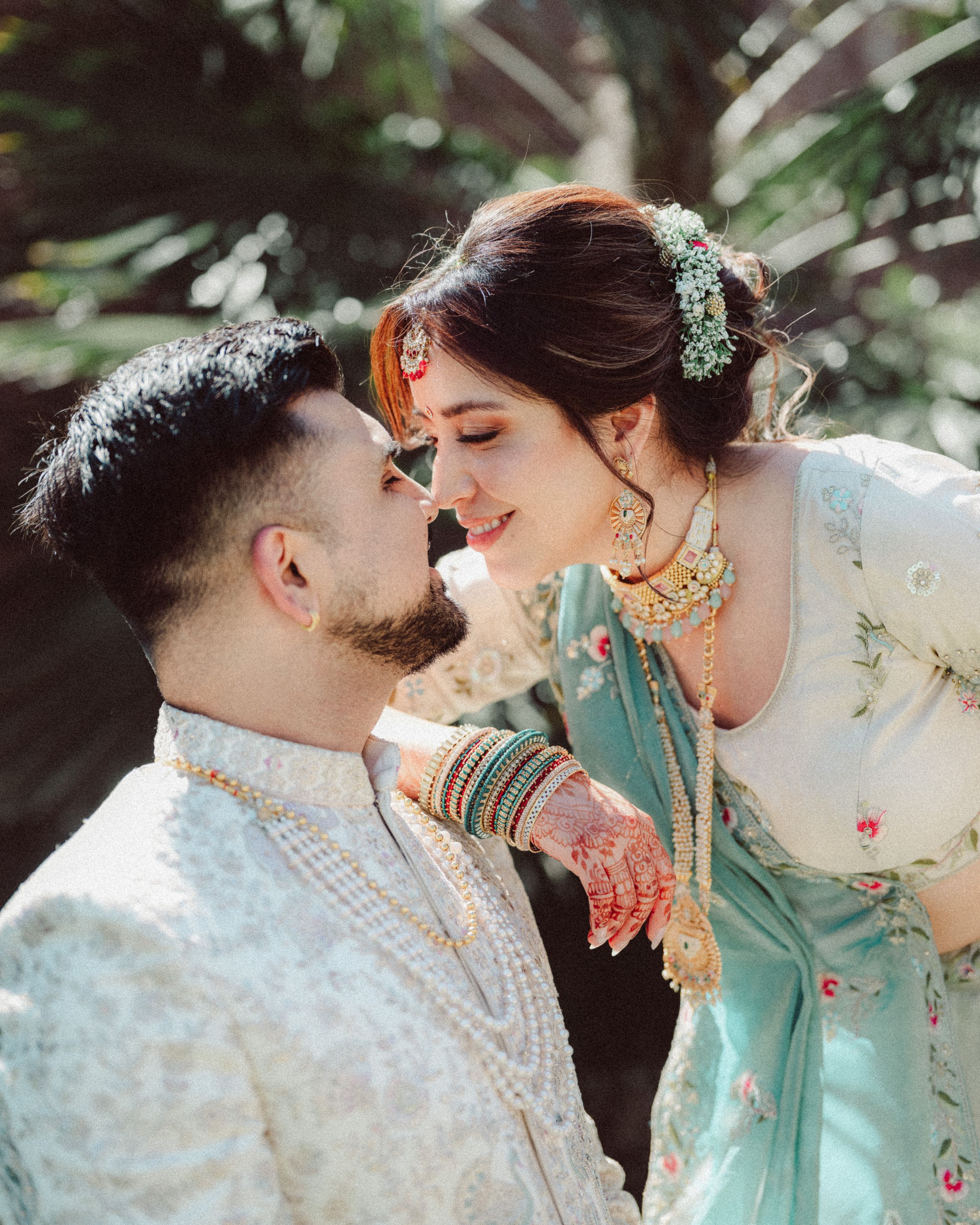 A romantic couple in traditional Indian wedding attire share intimate moments in a series of outdoor portrait photos.