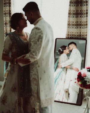 A couple shares an intimate moment during their wedding day in a room with tiled walls.