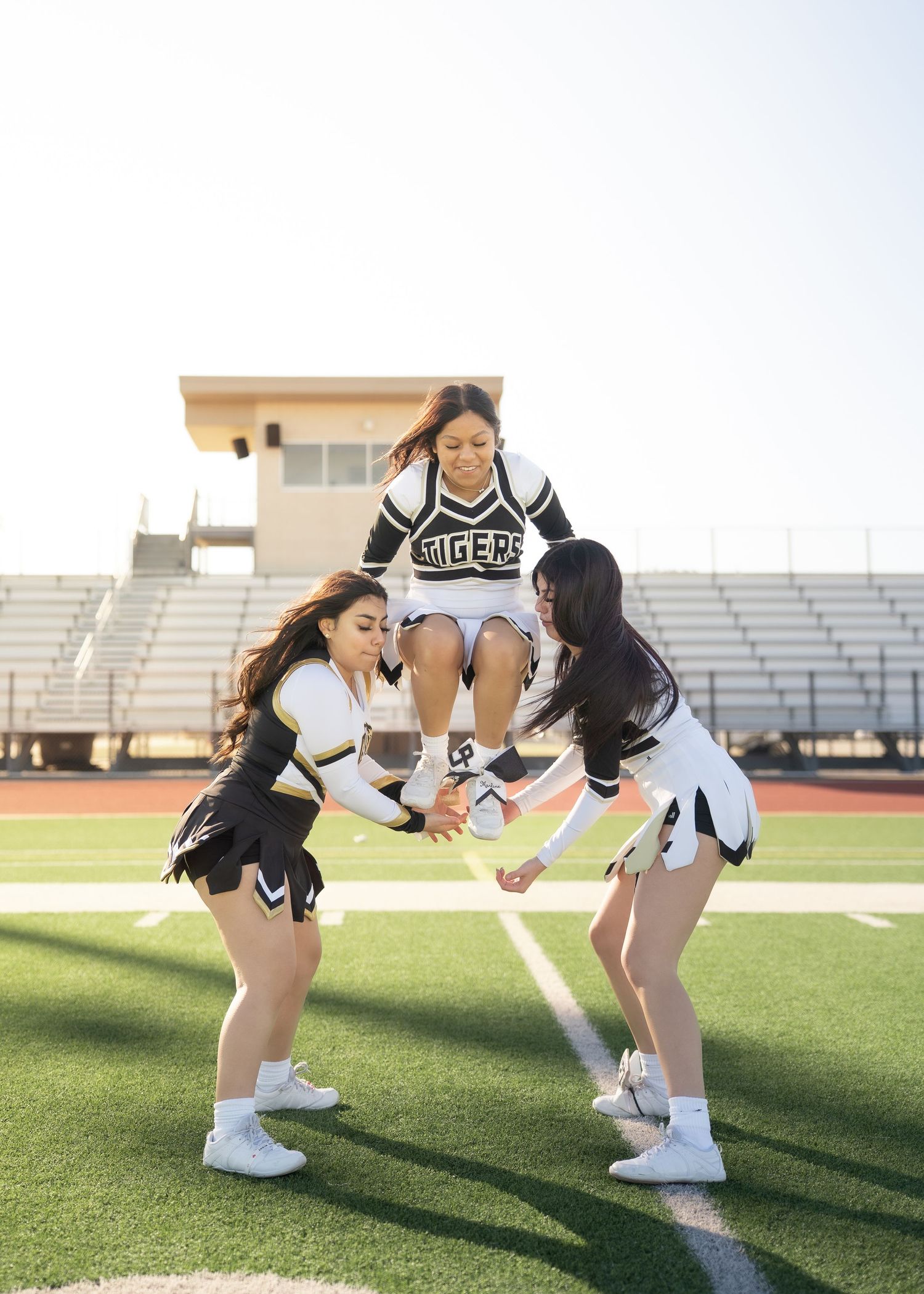 Cheerleaders tossing pom-poms in the air during outdoor group portrait