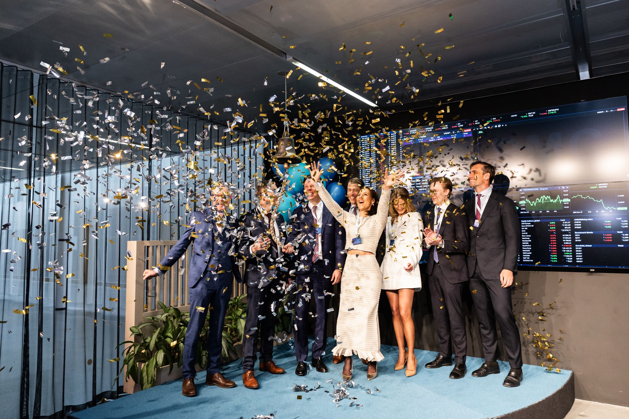 A group celebrates with confetti and champagne at a corporate event in a modern office space with city views. At Nasadaq i Stockholm.