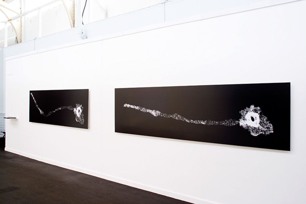 White gallery wall displaying series of black and white photographic prints.