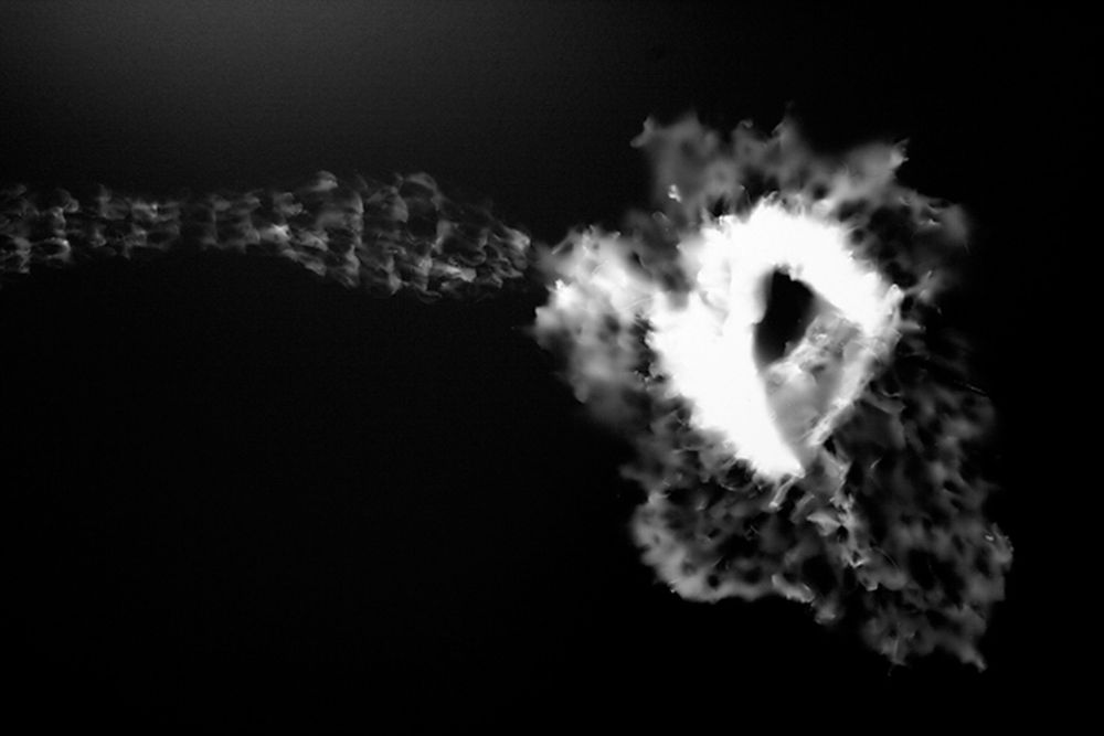 Abstract black and white smoke or cloud formations against dark background.