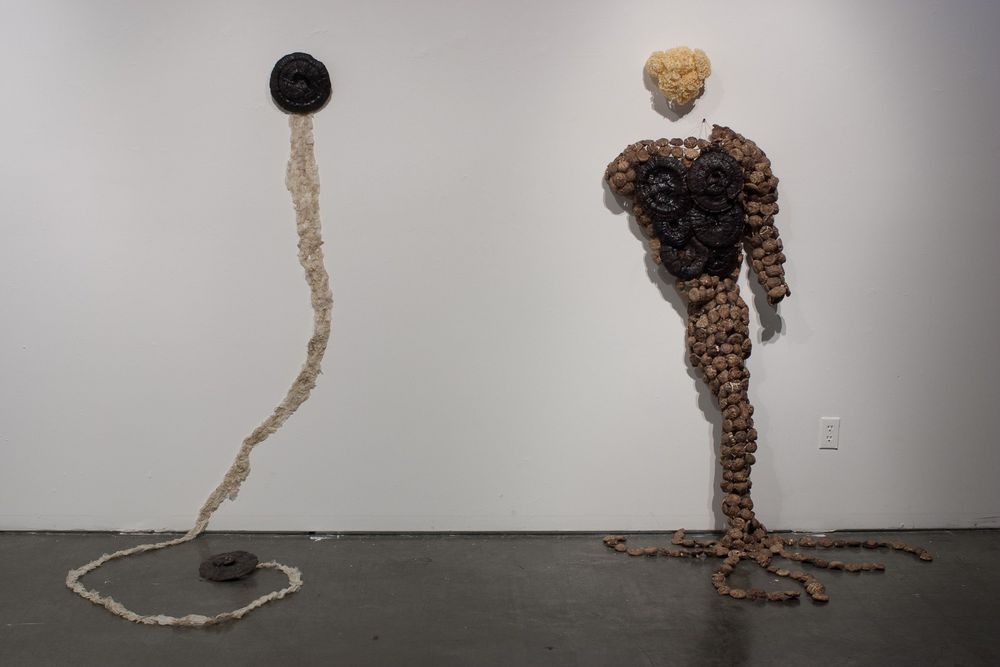 Abstract sculptural installation featuring dark spherical forms and rope-like elements.