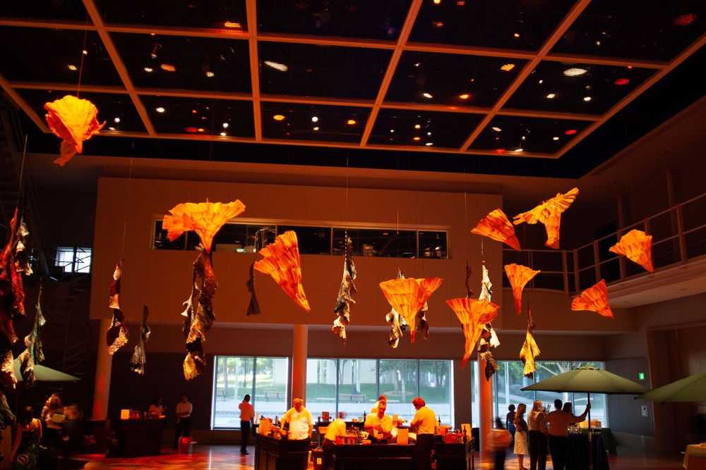 Orange paper lanterns and decorative stars hanging from a dark ceiling with spotlights.