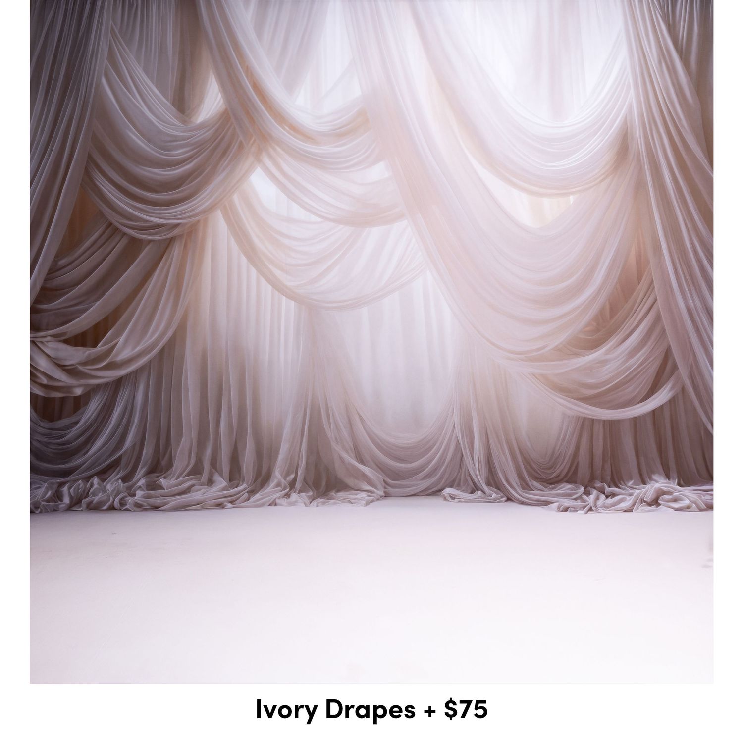 Elegant white draped fabric backdrop with cascading folds and soft lighting creating a romantic studio photography setting.