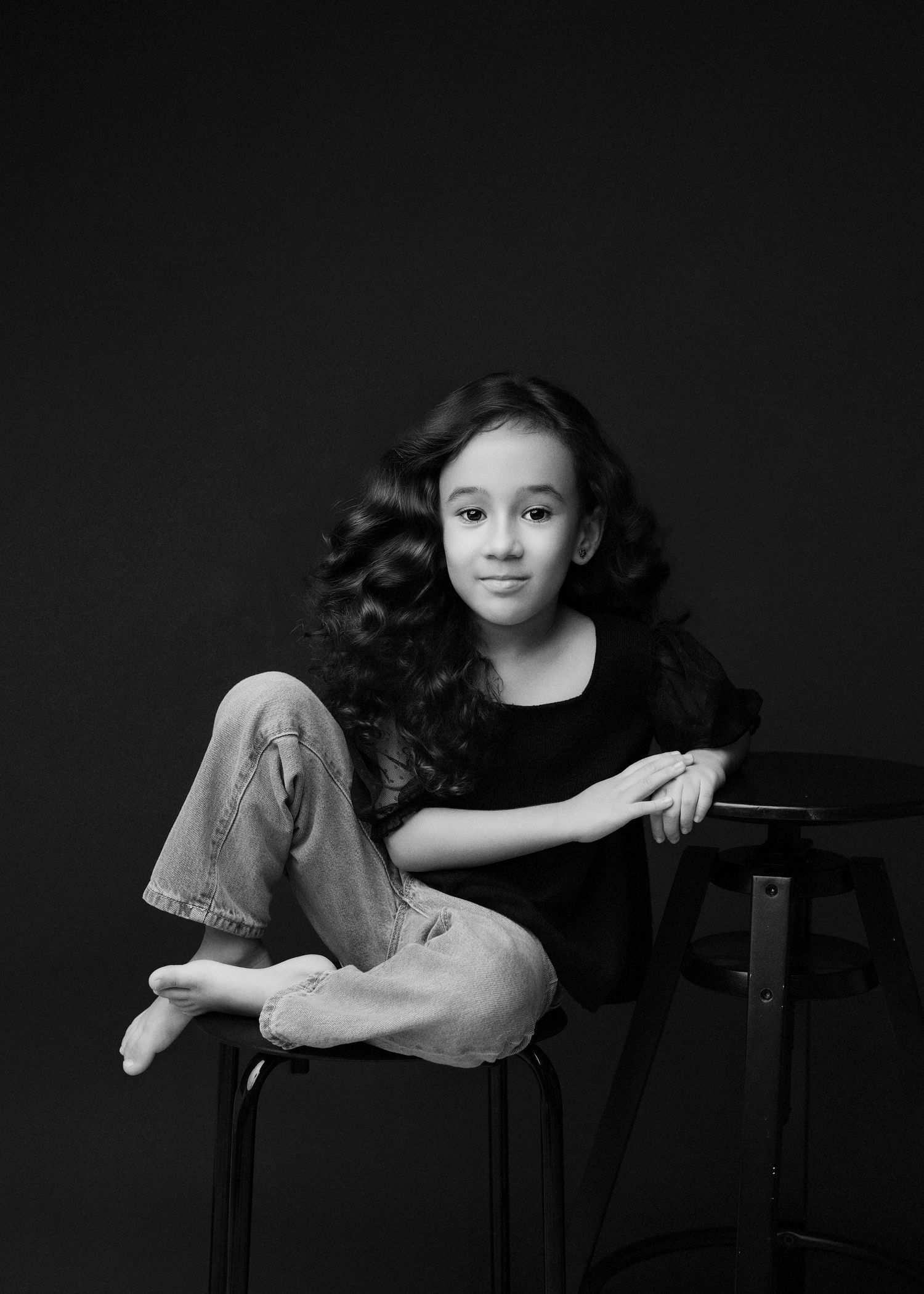 Black and white portrait series showing a young person with flowing dark hair in various expressive poses against dark background.
