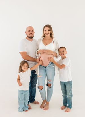 Family maternity photo shoot with casual matching outfits and distressed denim.
