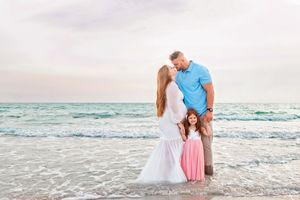 Beach family photoshoot at sunset with ocean waves in background.