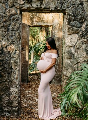 Maternity portraits against rustic stone ruins with lush tropical foliage.