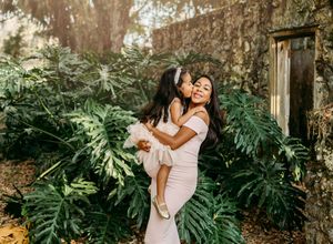 Intimate maternity photos in stone garden setting with monstera leaves and natural light.