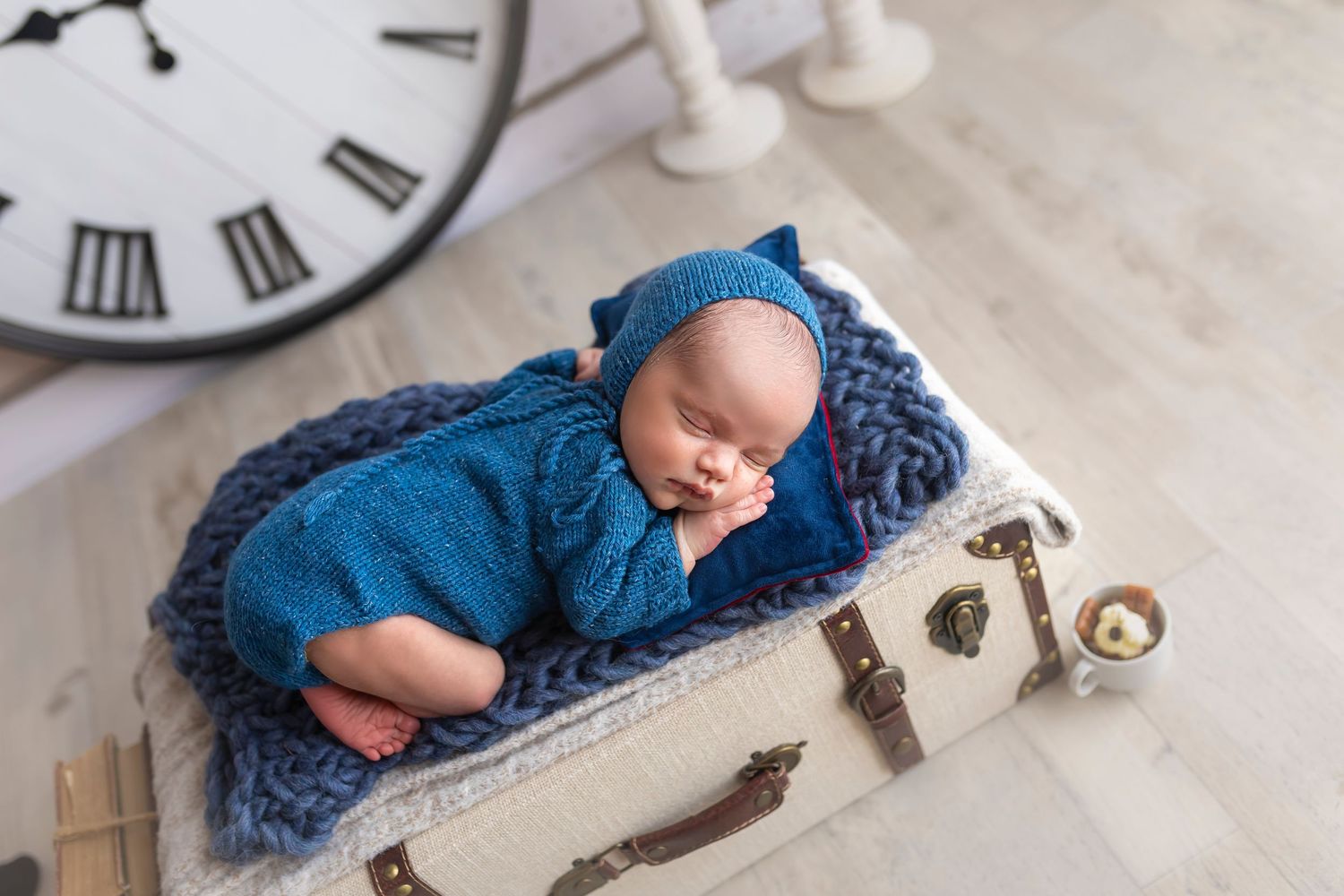 bebe recien nacido duermiendo encima de una maleta vestidito de azul