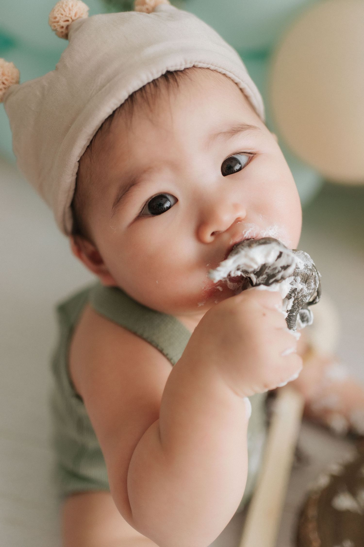 Close up of baby wearing white hat with chocolate frosting smeared on face during cake smash photo session.