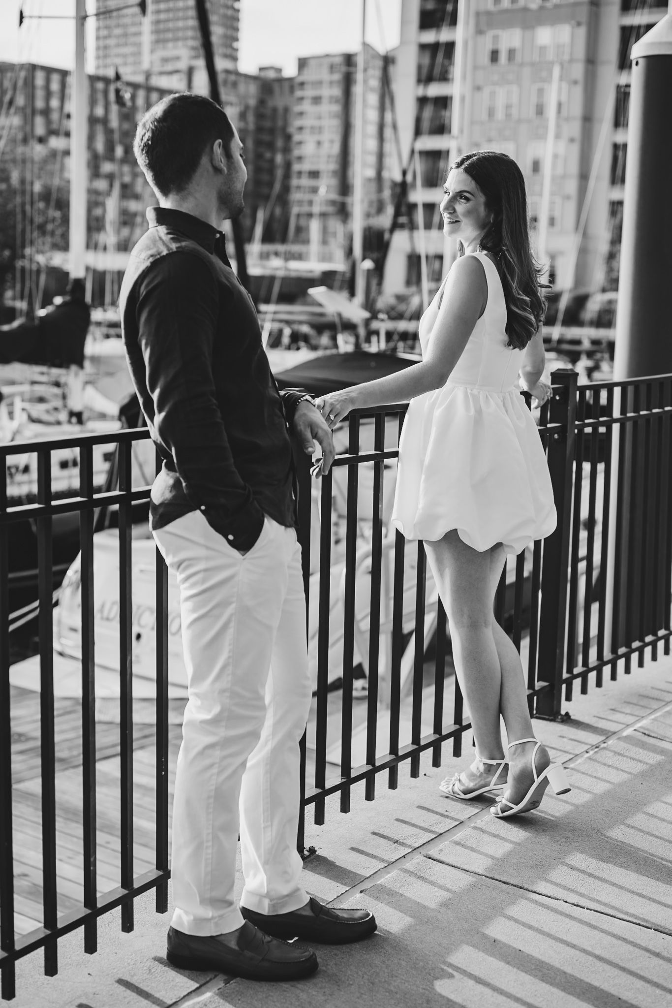 Black and white series showing couple interacting along waterfront railing.