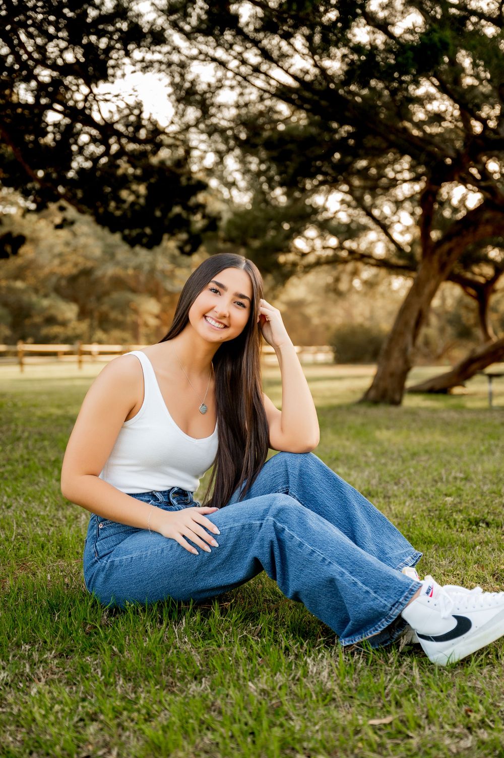Casual outdoor portrait featuring someone in denim and white lying on grass during golden hour.