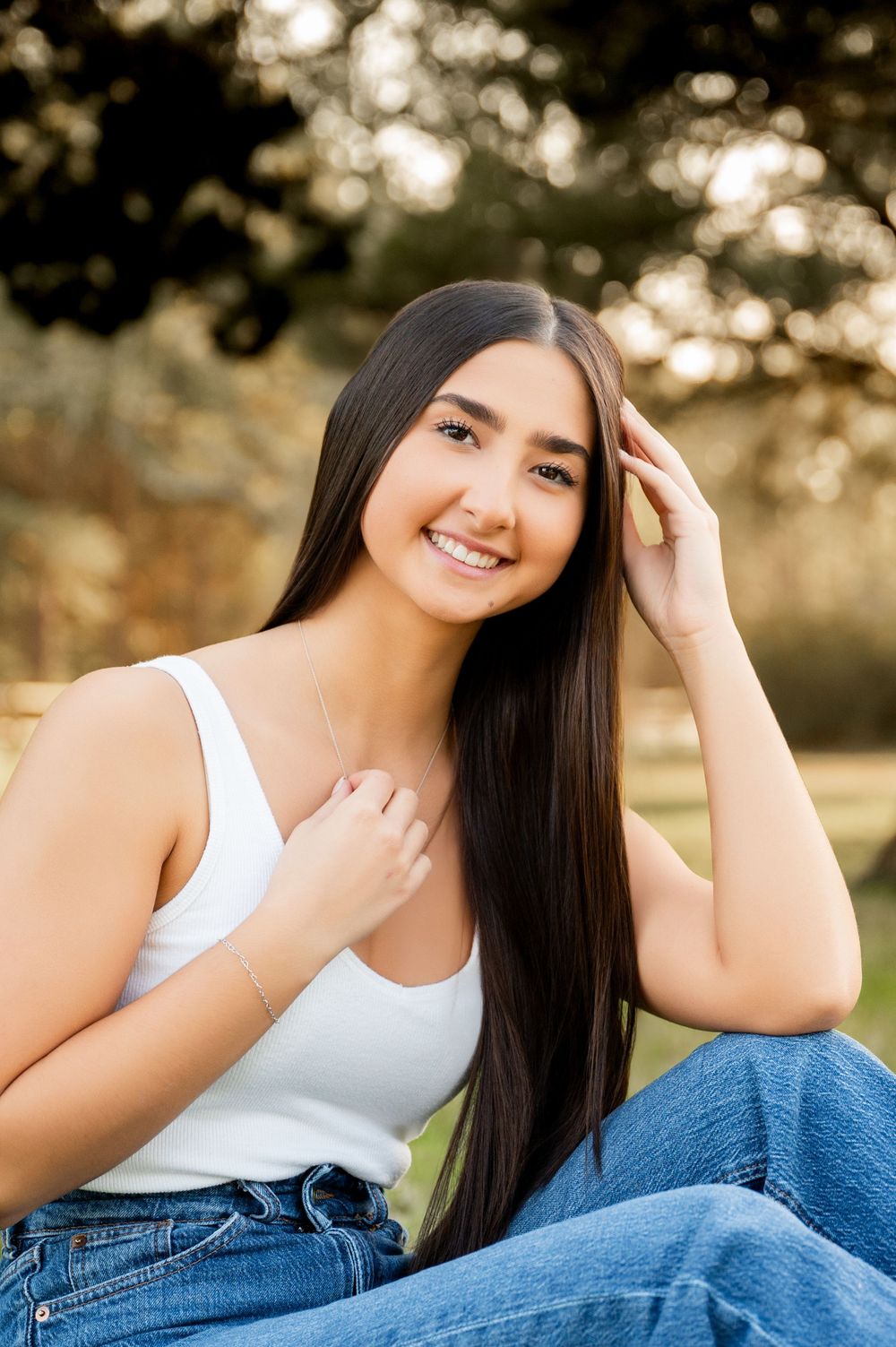 Relaxed outdoor portrait on grass wearing casual denim and white outfit during sunset.