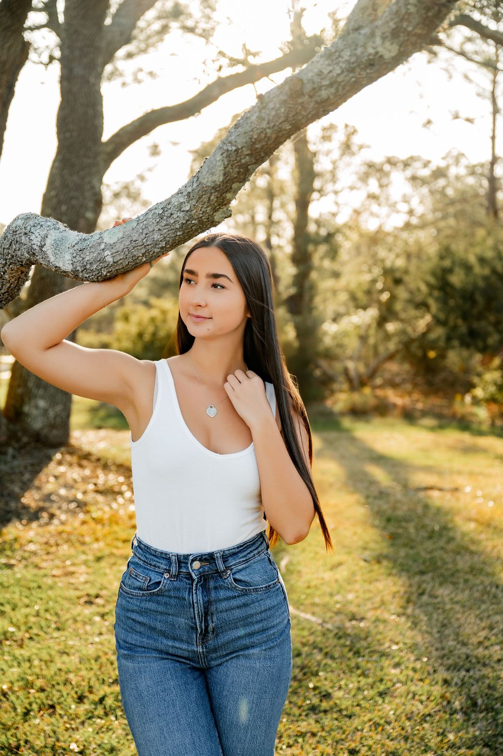 Casual outdoor portrait session featuring white tank top and jeans against natural backdrop.