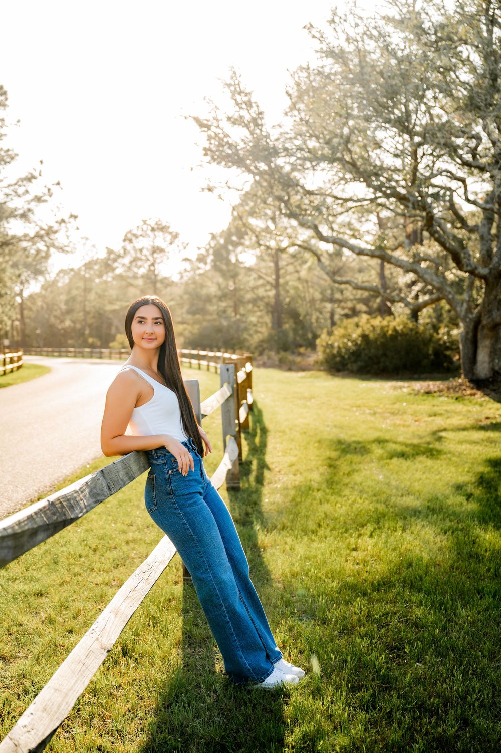 Outdoor portrait session on grassy hill with sunlit trees in background.