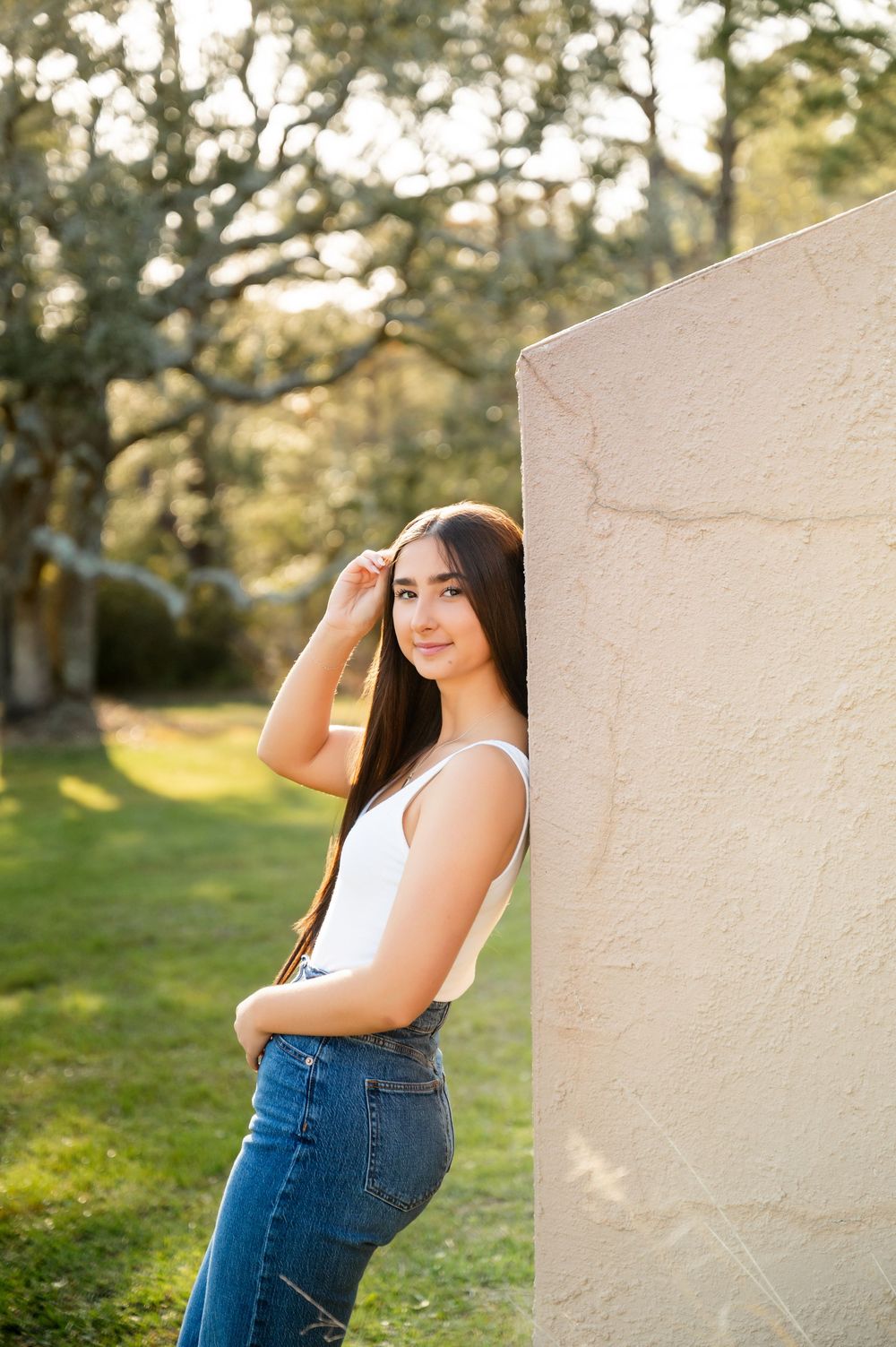 Portrait session against white wall with natural lighting and outdoor scenery.