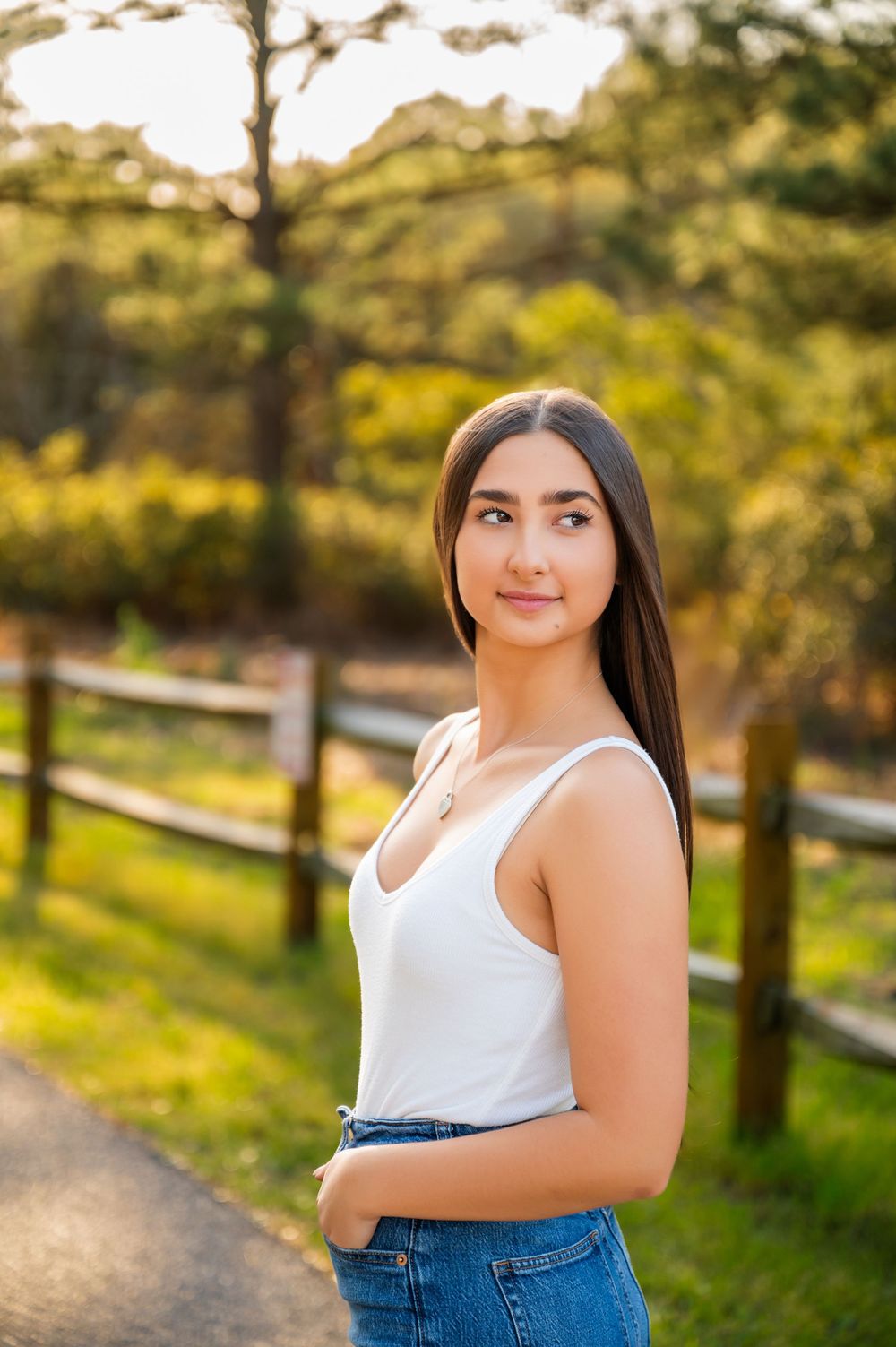 Casual outdoor portrait featuring white tank top and jeans in golden sunset lighting.