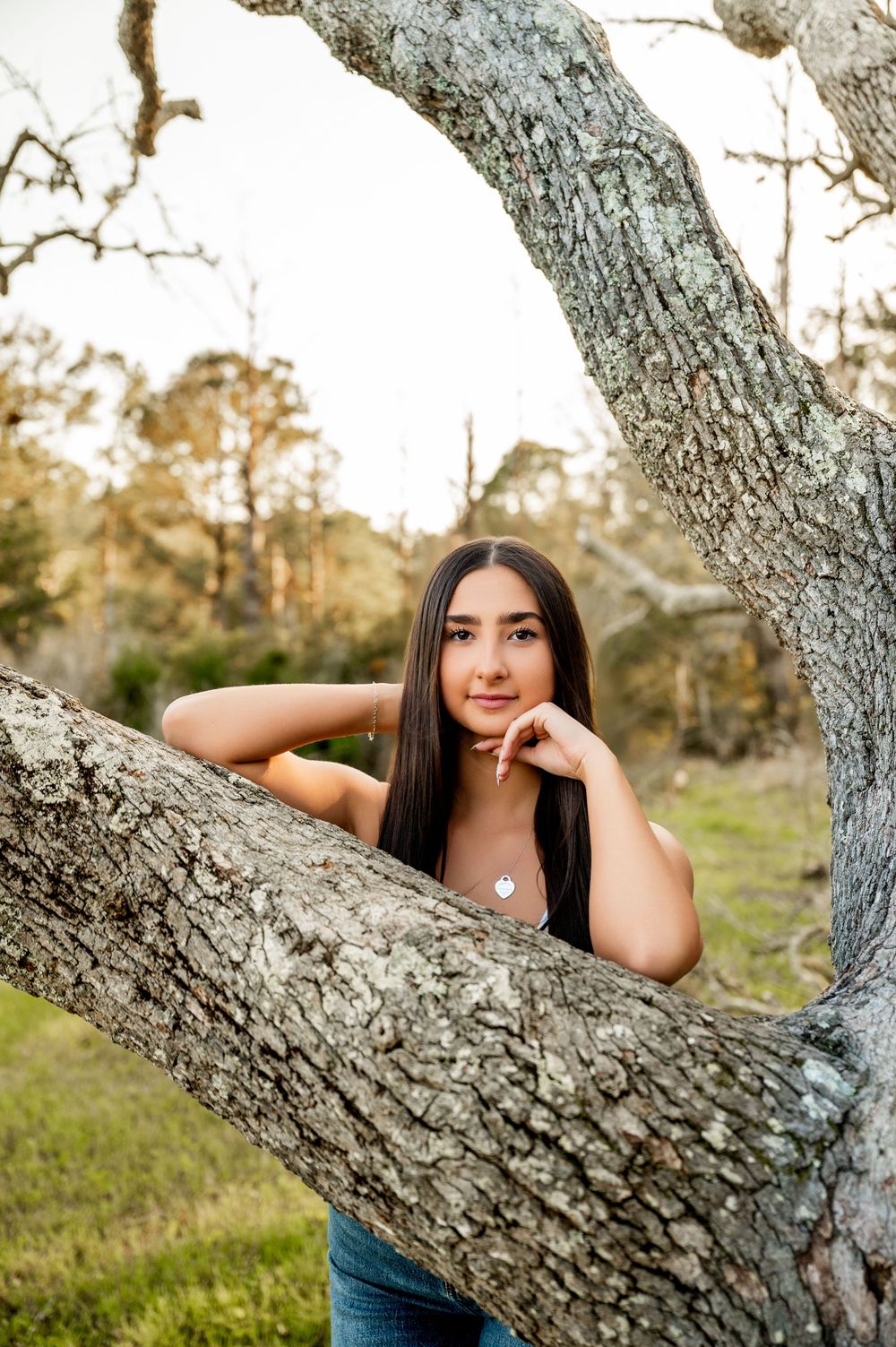 Casual portrait session featuring someone lounging on a large tree branch in an outdoor setting.