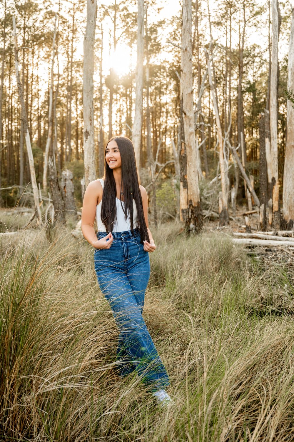 Artistic portrait in a wooded area with tall grass and eucalyptus trees at sunset.