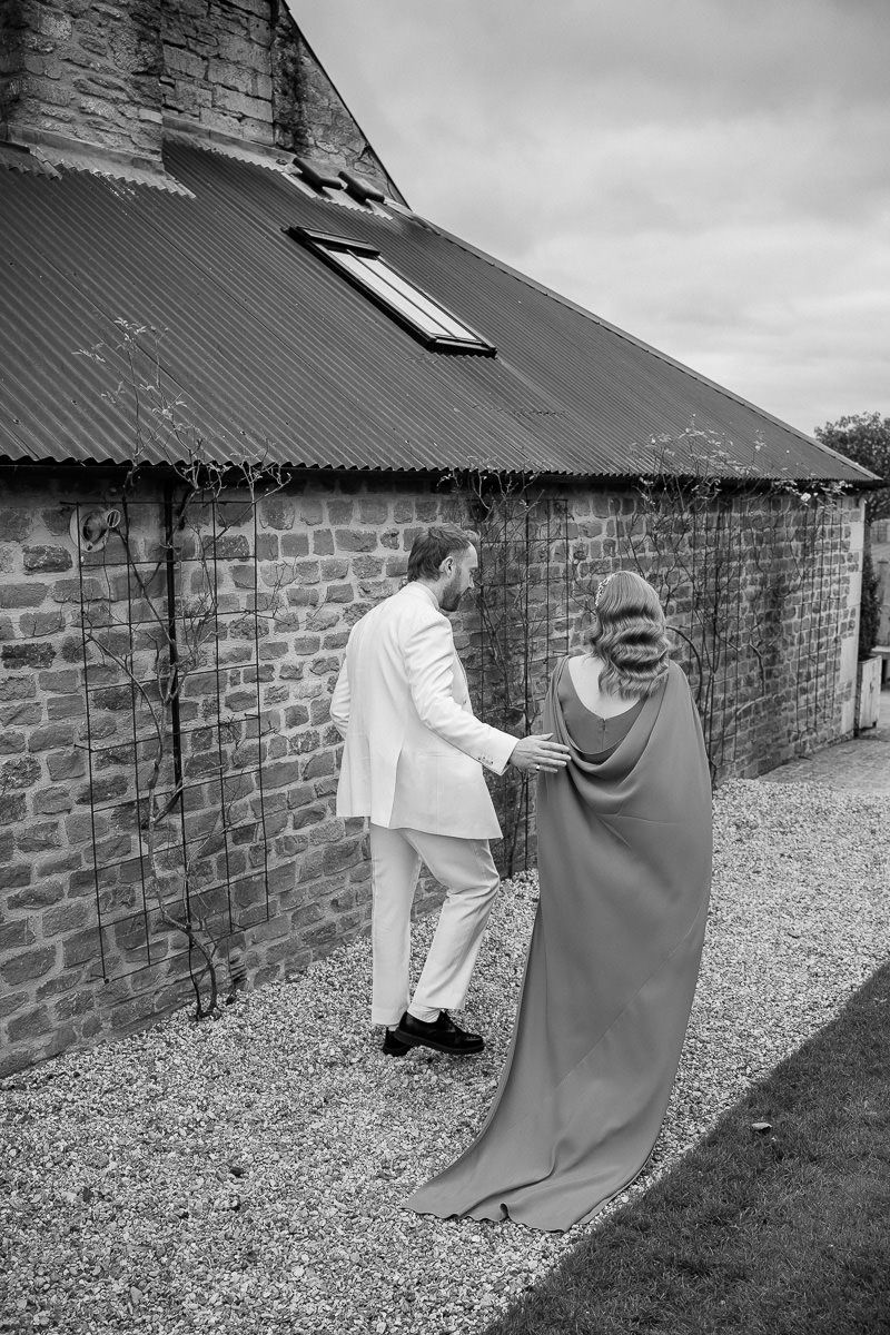 A sequence of black and white photos showing a figure in white chasing another figure in dark clothing along a brick wall.