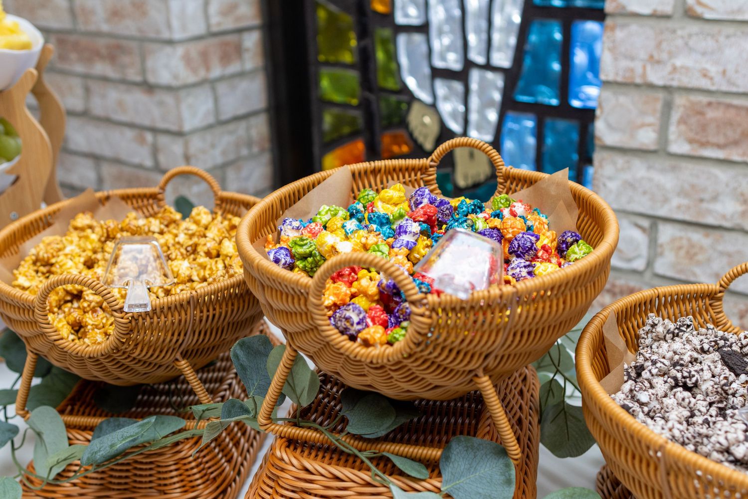 Wicker baskets filled with colorful gourmet popcorn at a catholic reception, dessert table, photographed at a Magnolia TX wedding venue.