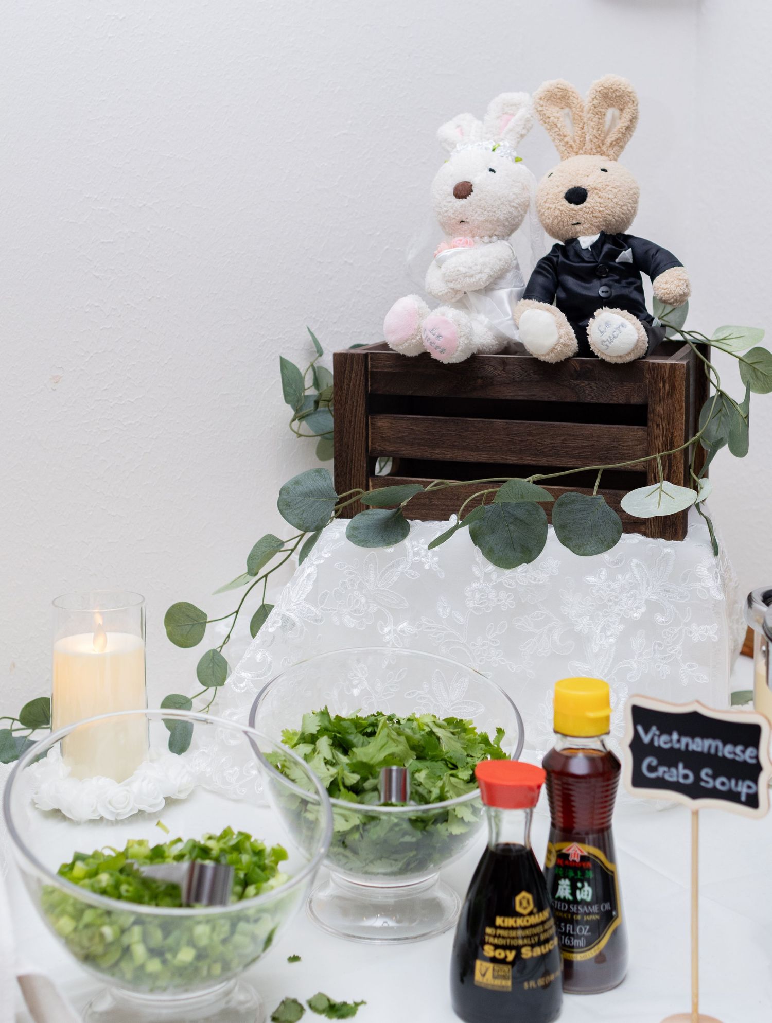 A rustic wooden shelf decorated with plush bunnies, greenery, and glowing candles creates a cozy and cute wedding display.