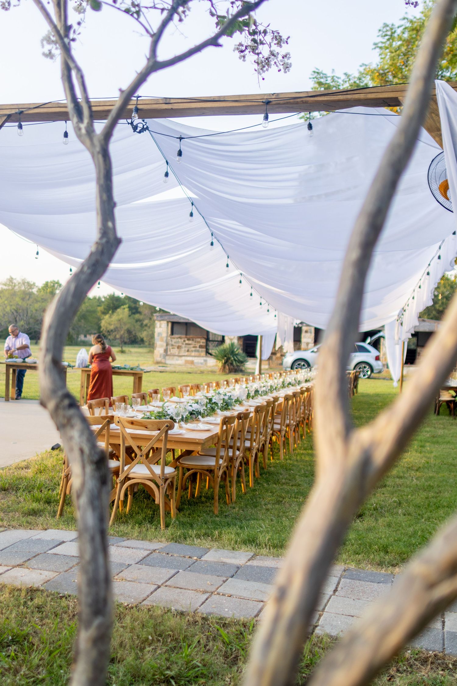 Outdoor wedding reception under flowing white drapery with long banquet tables and scenic countryside views in East Texas.