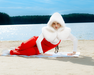 Artistic beach photoshoot featuring a red dress and white fur against a waterfront backdrop.