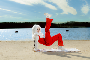 Abstract artistic movements captured on a beach showing flowing red and white fabric against the shoreline.