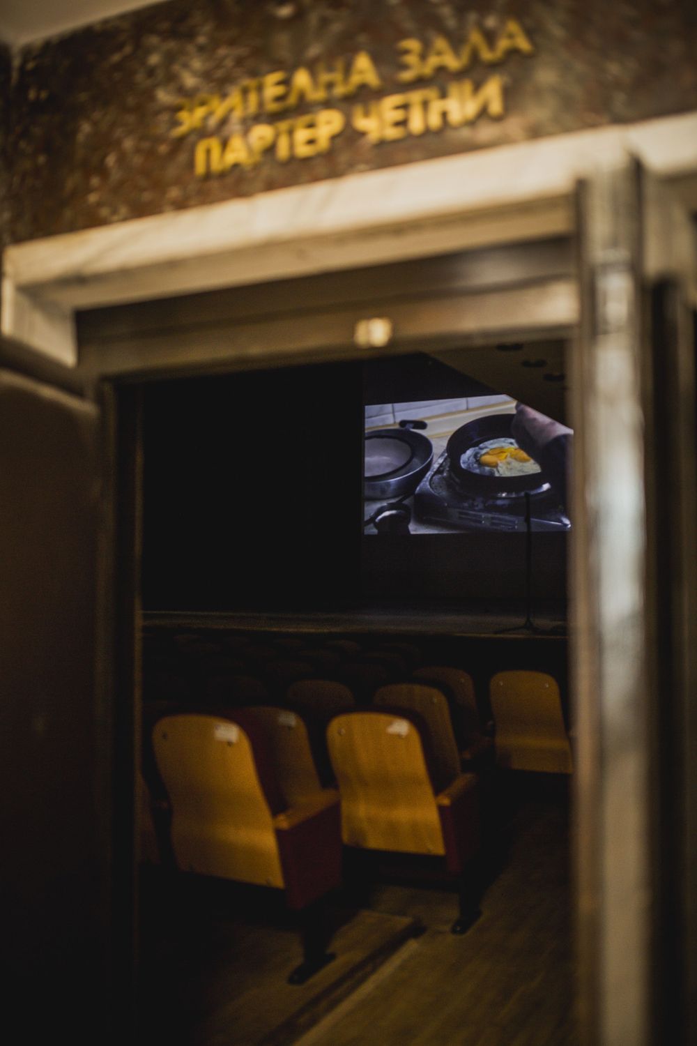 View through theater doorway showing vintage seats and film screening on screen.