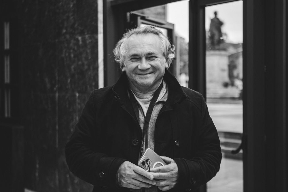 Cheerful older man smiling outdoors in black and white portrait photo.